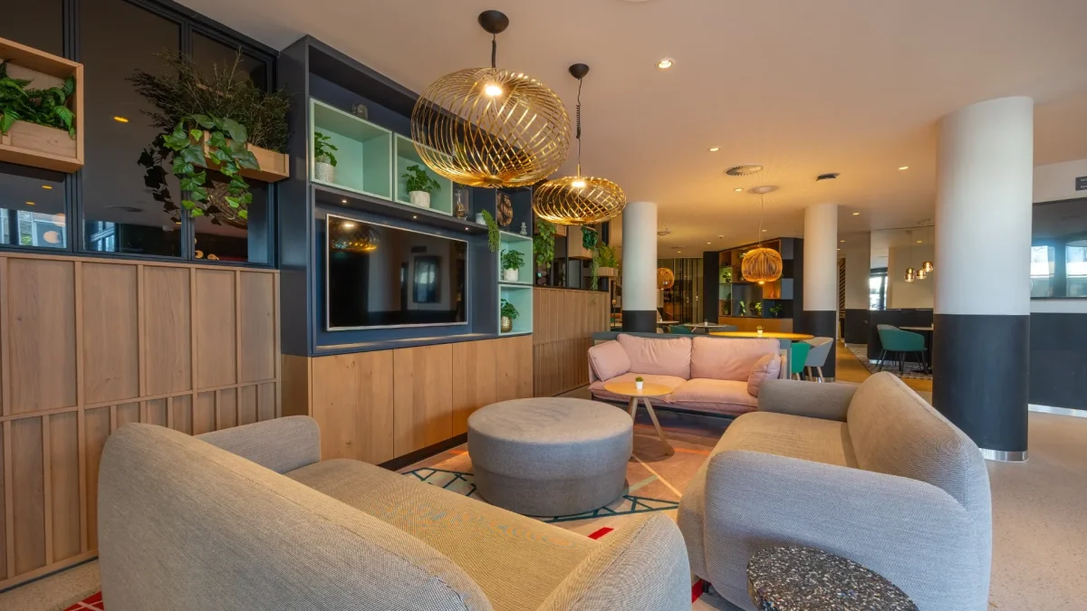Lobby with armchairs, plants and gold pendant lights
